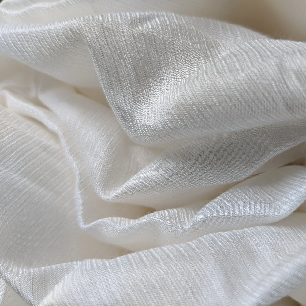 Pure white milk cellulose fabric rolled on a bolt, showcasing its sheen.
