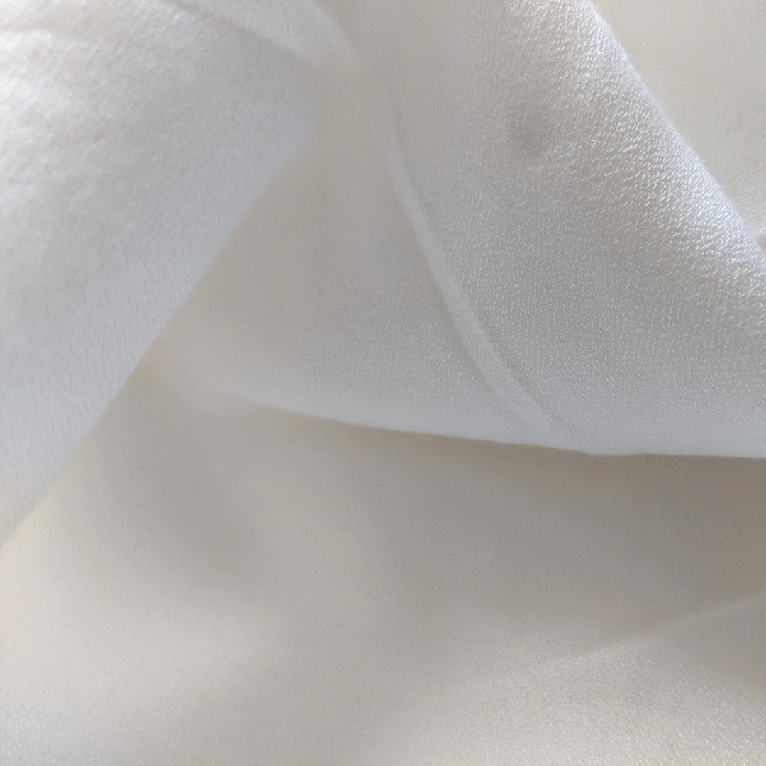 Natural off-white milk fabric displayed flat, ideal for fashion applications.